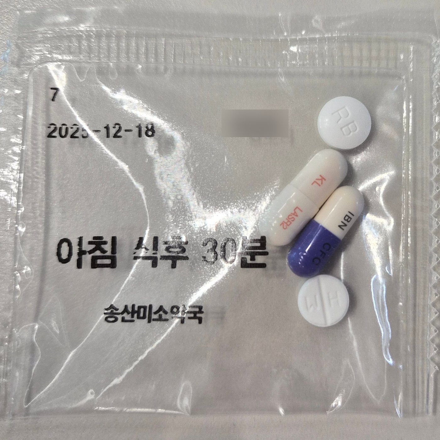알약 여러 개가 담긴 투명 약포지를 위에서 찍은 사진